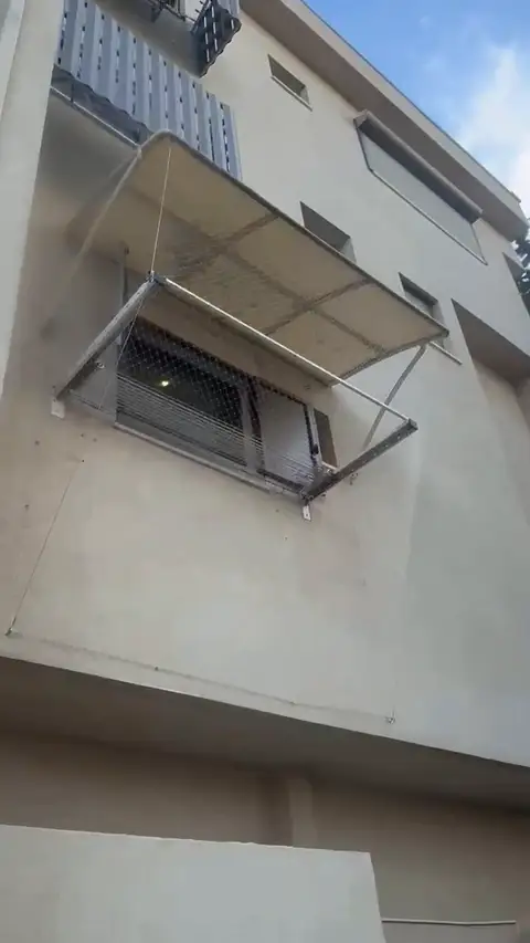 רשת נגד יונים על גגון ומסביב למתלה כביסה בחזית בניין